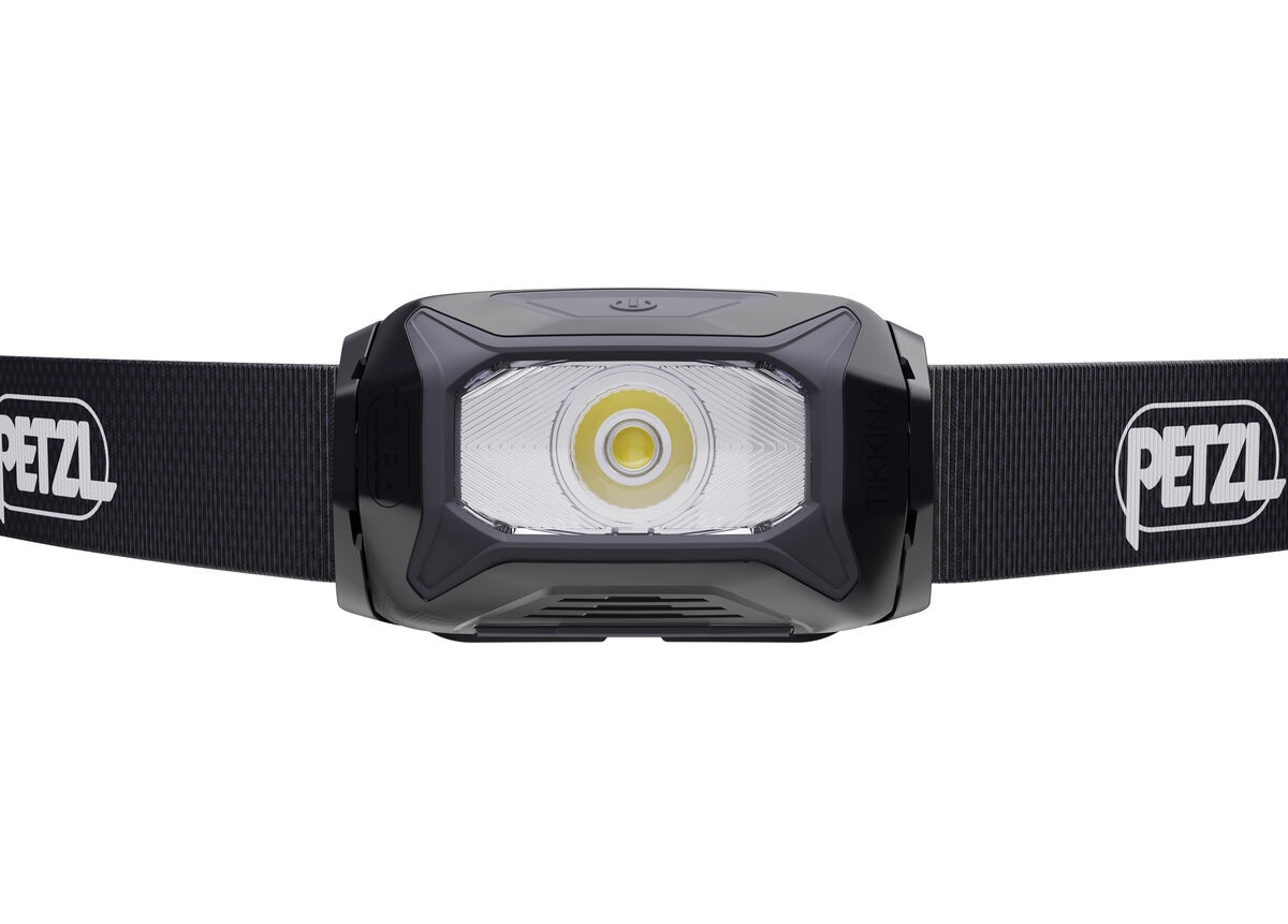 Petzl TIKKINA zblízka spredu — v priehľadnej optike jedna veľká biela LED so žltým fosforom, po stranách čierne telo a čierny pásik s logom Petzl