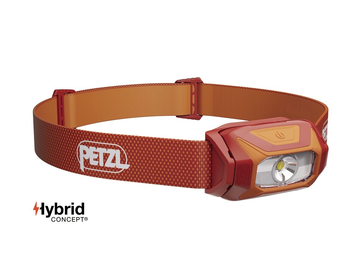 Petzl TIKKINA 2025 v červenej farbe — tehlovočervené telo s oranžovým rámom optiky a červený pásik s oranžovou vnútornou stranou