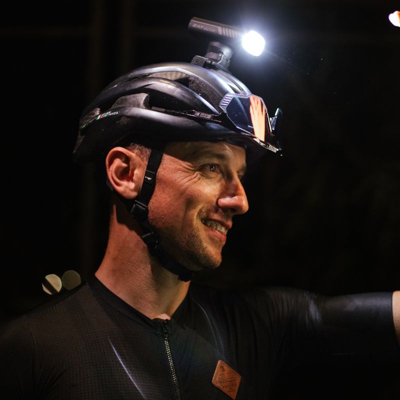 Cyklista s cyklosvetlom Magicshine RAY 1600B upevneným na prilbe cez GoPro adaptér počas nočnej jazdy