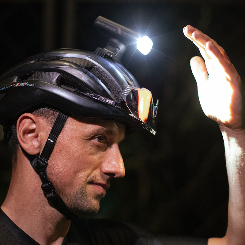 Cyklista s cyklosvetlom Magicshine RAY 2600B upevneným na prilbe cez GoPro adaptér počas nočnej jazdy