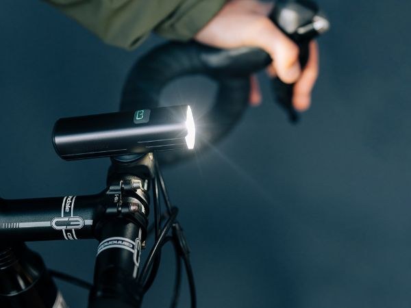 Magicshine RN1500 svieti na riadidlách cestného bicykla, ruka cyklistu drží spodnú časť baranov