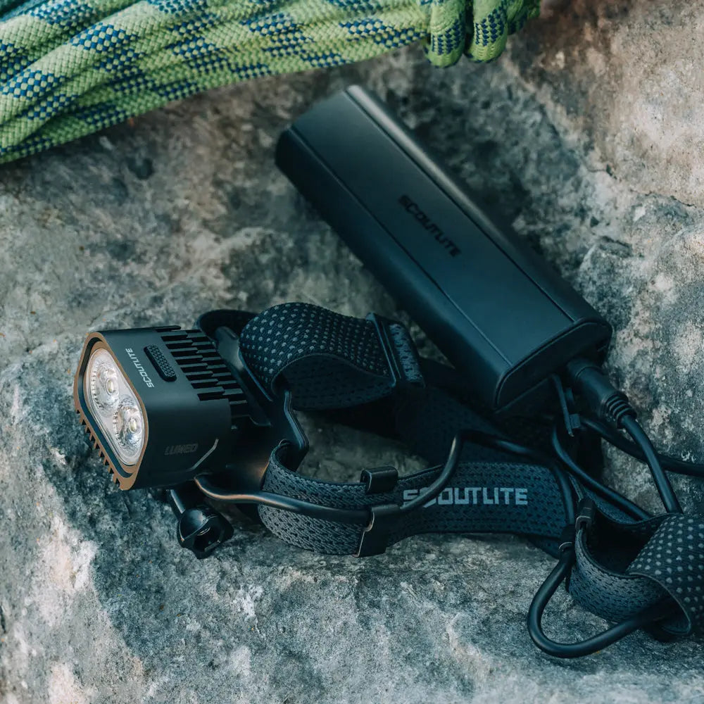 Scoutlite LUMEO 4000 s battery packom a horolezeckým lanom na skale, popruh s nápisom SCOUTLITE