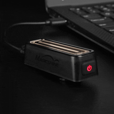 Zadné svetlo Magicshine SEEMEE 100 V2.0 sa nabíja pripojené káblom k notebooku, tlačidlo svieti načerveno