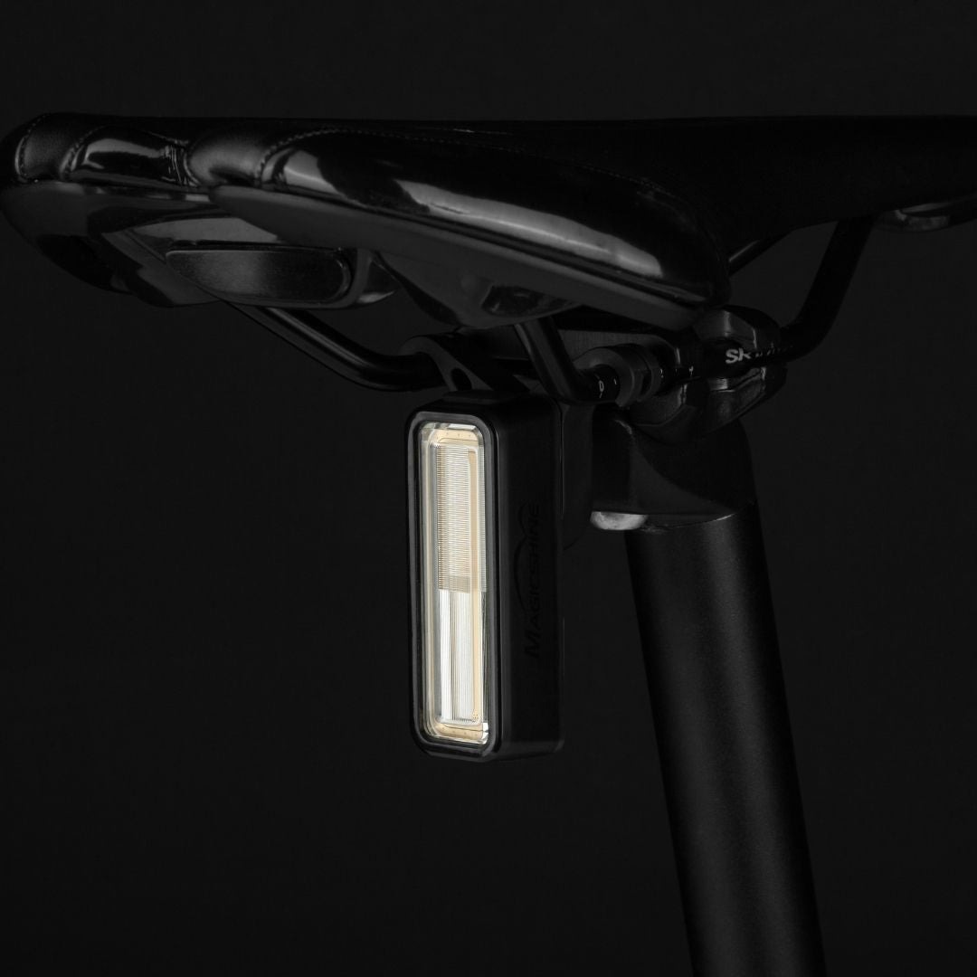 Magicshine SEEMEE 180 — zadné svetlo na bicykel upnuté pod sedlom na sedlovke, so svetelným pásom cez celú prednú stenu