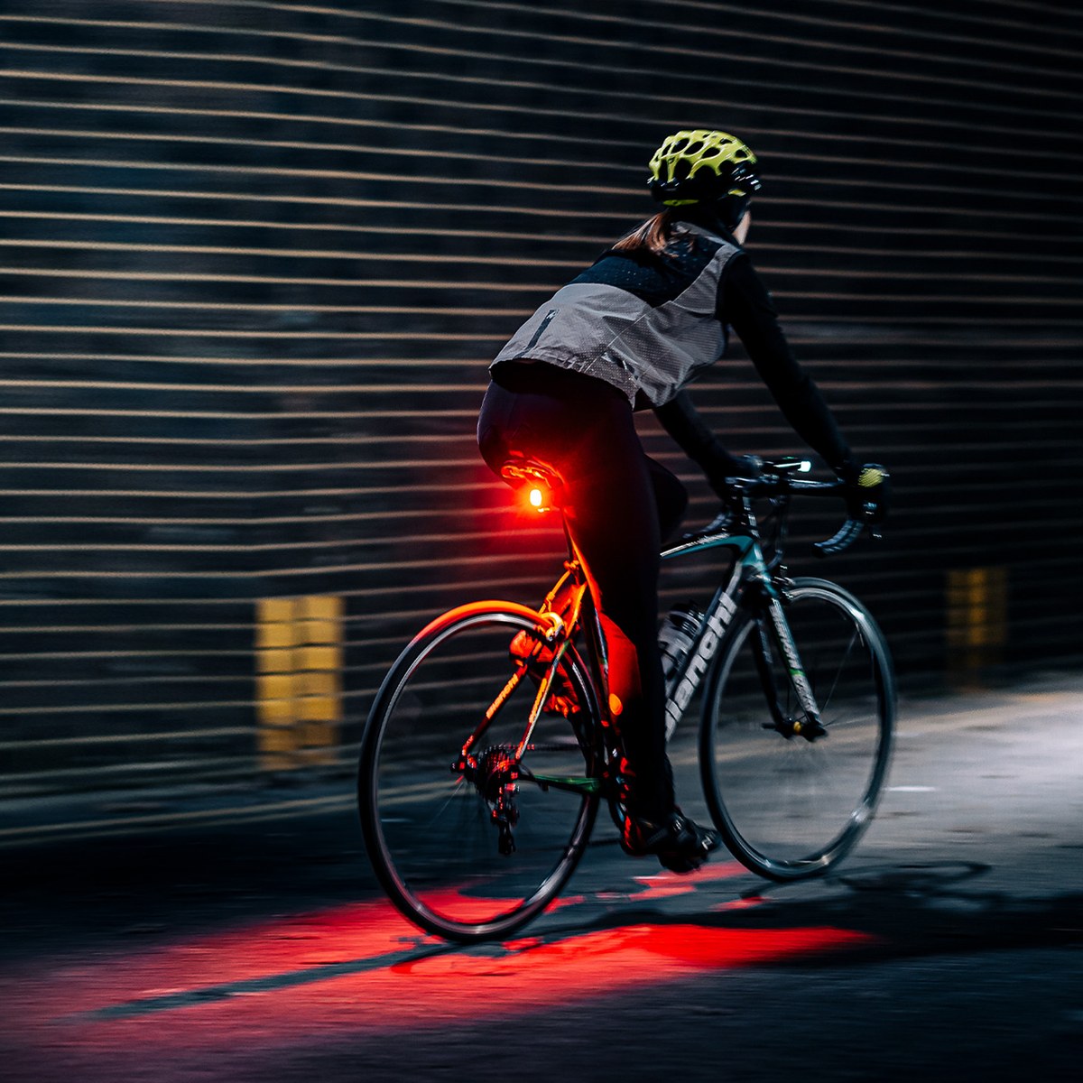 Cyklistka v noci so zadným svetlom Magicshine SEEMEE 200 V3.0, senzor okolitého svetla prispôsobuje jas prostrediu