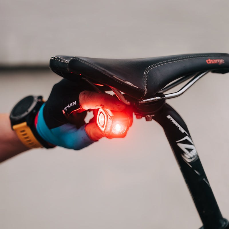 Ruka nasadzuje svietiace zadné svetlo Magicshine SEEMEE 200 V3.0 na držiak na lyžinách sedla bicykla