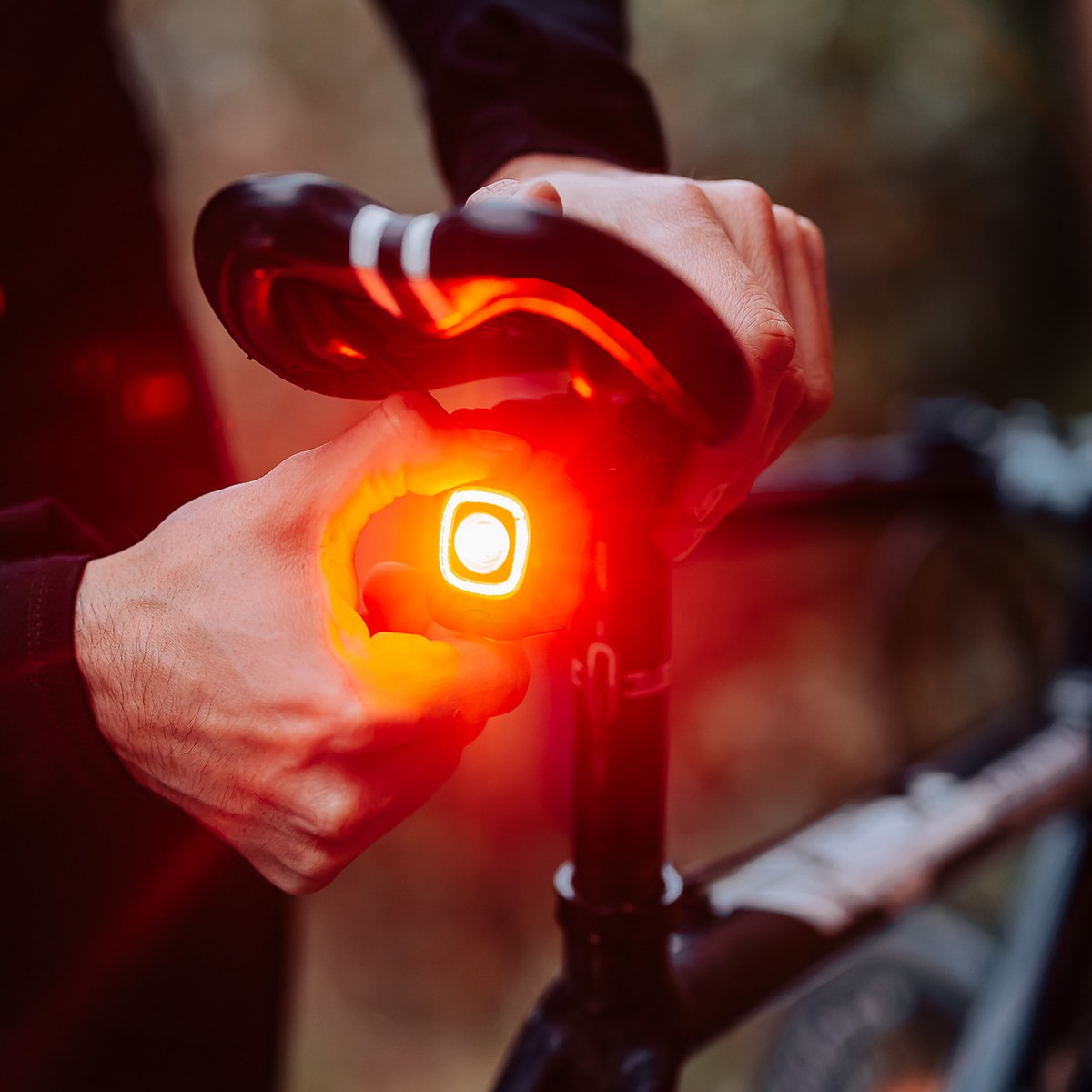 Ruky nasadzujú zadné svetlo Magicshine SEEMEE 200 V3.0 na remienkový držiak na sedlovke bicykla