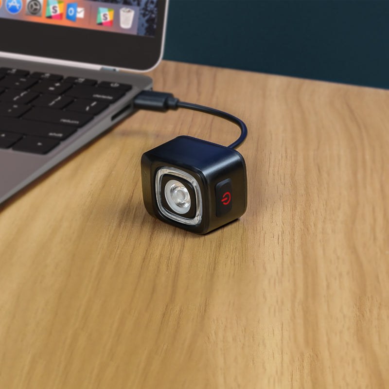 Zadné svetlo Magicshine SEEMEE 200 V3.0 sa nabíja káblom USB-C z notebooku, na boku je vidieť tlačidlo
