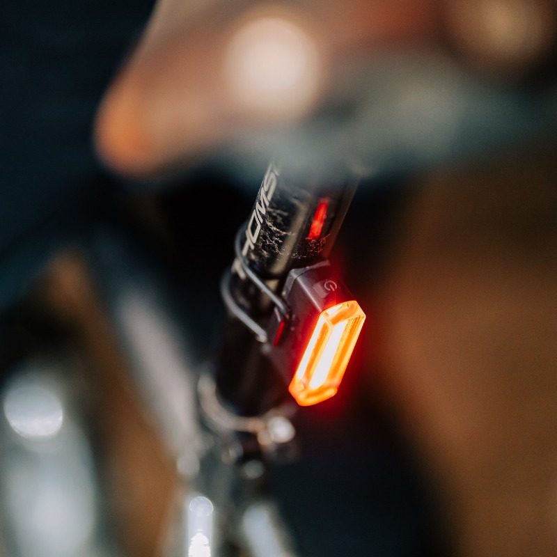 Zadné svetlo Magicshine SEEMEE 20 V2.0 nasadené na sedlovke bicykla pod sedlom, rozsvietené