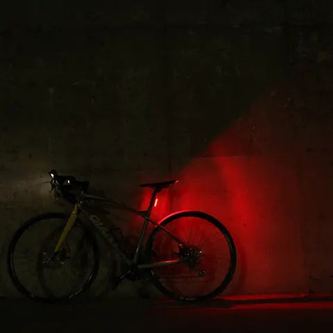 Bicykel pri betónovej stene za tmy, zadné svetlo Magicshine SEEMEE 30 V2.0 vytvára široký červený svit