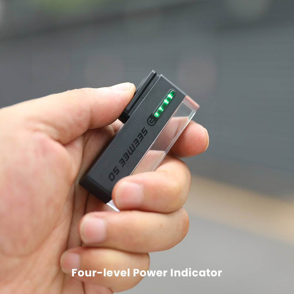 Magicshine SEEMEE 50 PRO v ruke so štyrmi svietiacimi zelenými segmentmi indikátora batérie, grafika výrobcu Four-level Power Indicator