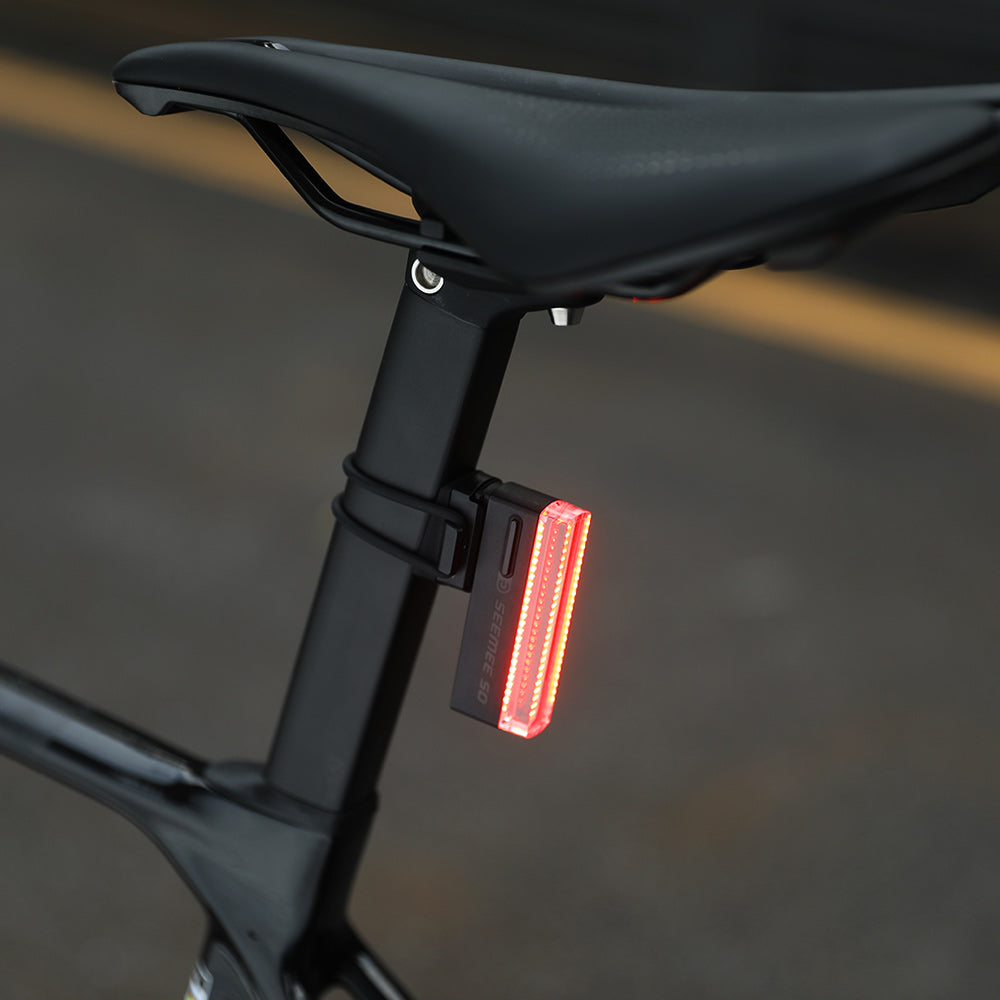 Magicshine SEEMEE 50 PRO svieti načerveno na sedlovke cestného bicykla, pohľad zblízka pri dennom svetle