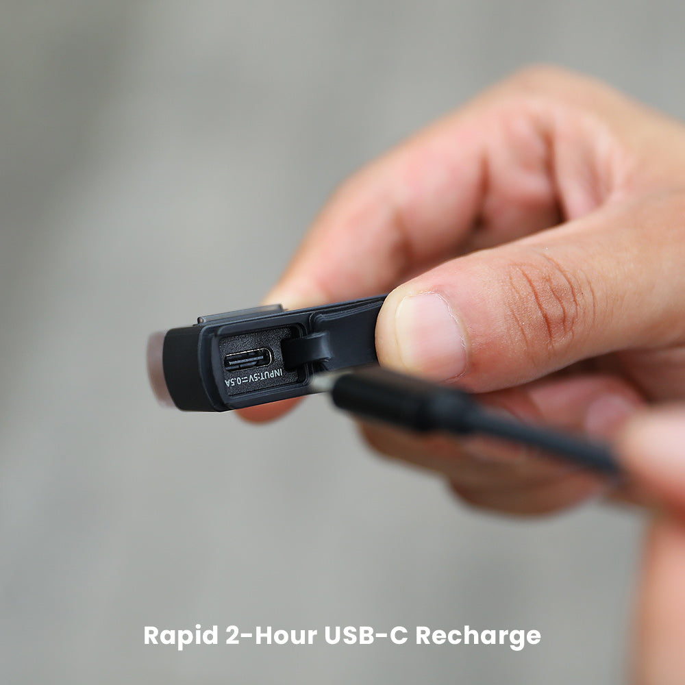 Detail nabíjacieho konektora USB-C na Magicshine SEEMEE 50 PRO pod odklopenou gumovou krytkou, svetlo držané v ruke