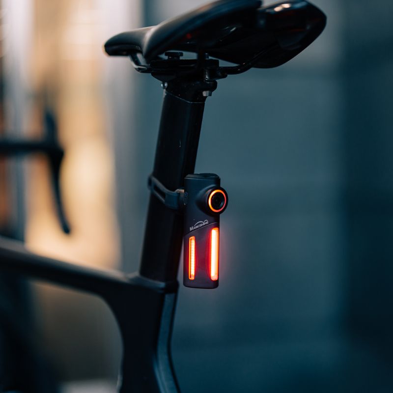 Magicshine SEEMEE DV upnuté na sedlovke cestného bicykla za šera, svieti načerveno dvoma svetelnými pásmi