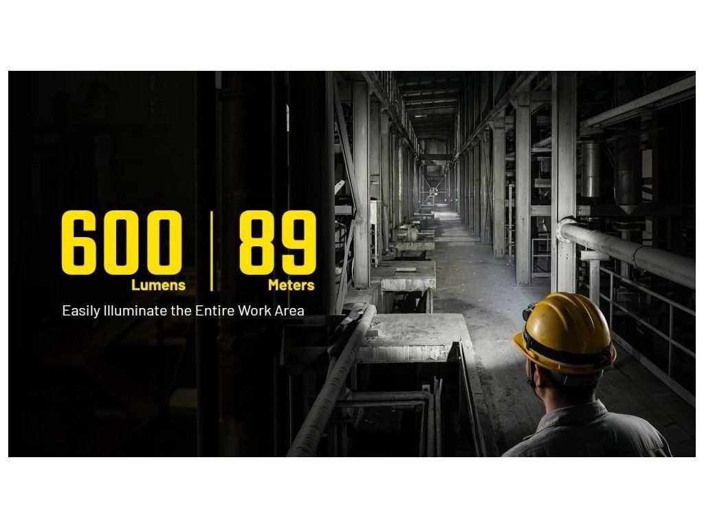 NITECORE NWH20 na prilbe pracovníka osvetľuje dlhú priemyselnú halu – svetelný tok 600 lm a dosvit 89 metrov