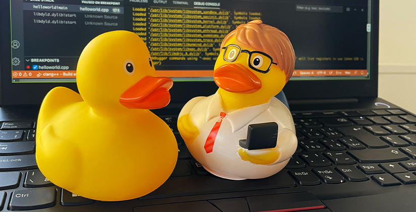 Gumová kachnička na pracovním stole programátora, symbol metody Rubber Duck Debugging, která pomáhá při hledání chyb v kódu.
