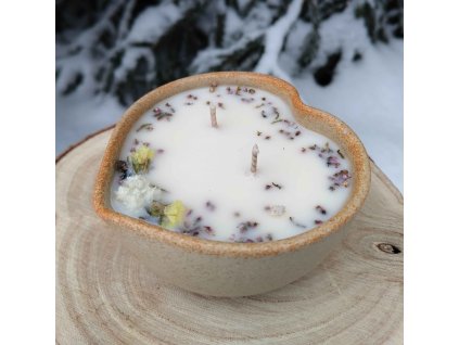 Dekorační svíčka s minerály a jemnými kvítky v misce z kameniny ve tvaru srdce.