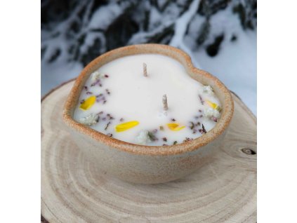 Dekorační svíčka s minerály a jemnými kvítky v misce z kameniny ve tvaru srdce.