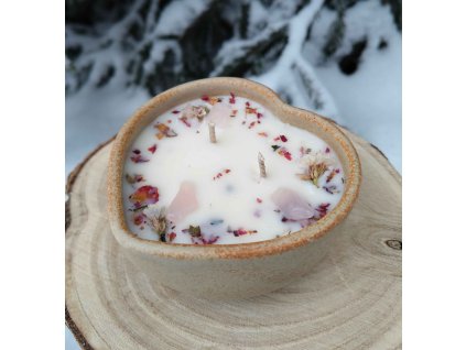 Dekorační svíčka s minerály a jemnými kvítky v misce z kameniny ve tvaru srdce.