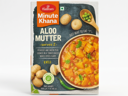 Photorealistic 3D render of Haldiram's Minute Khana Aloo Mutter packet on clean white background. The packet is rectangular with dark grey blue textured background. Top left shows orange rectangular panel with white