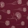 Režná látka v metráži s motivem pampelišek na červeném podkladu