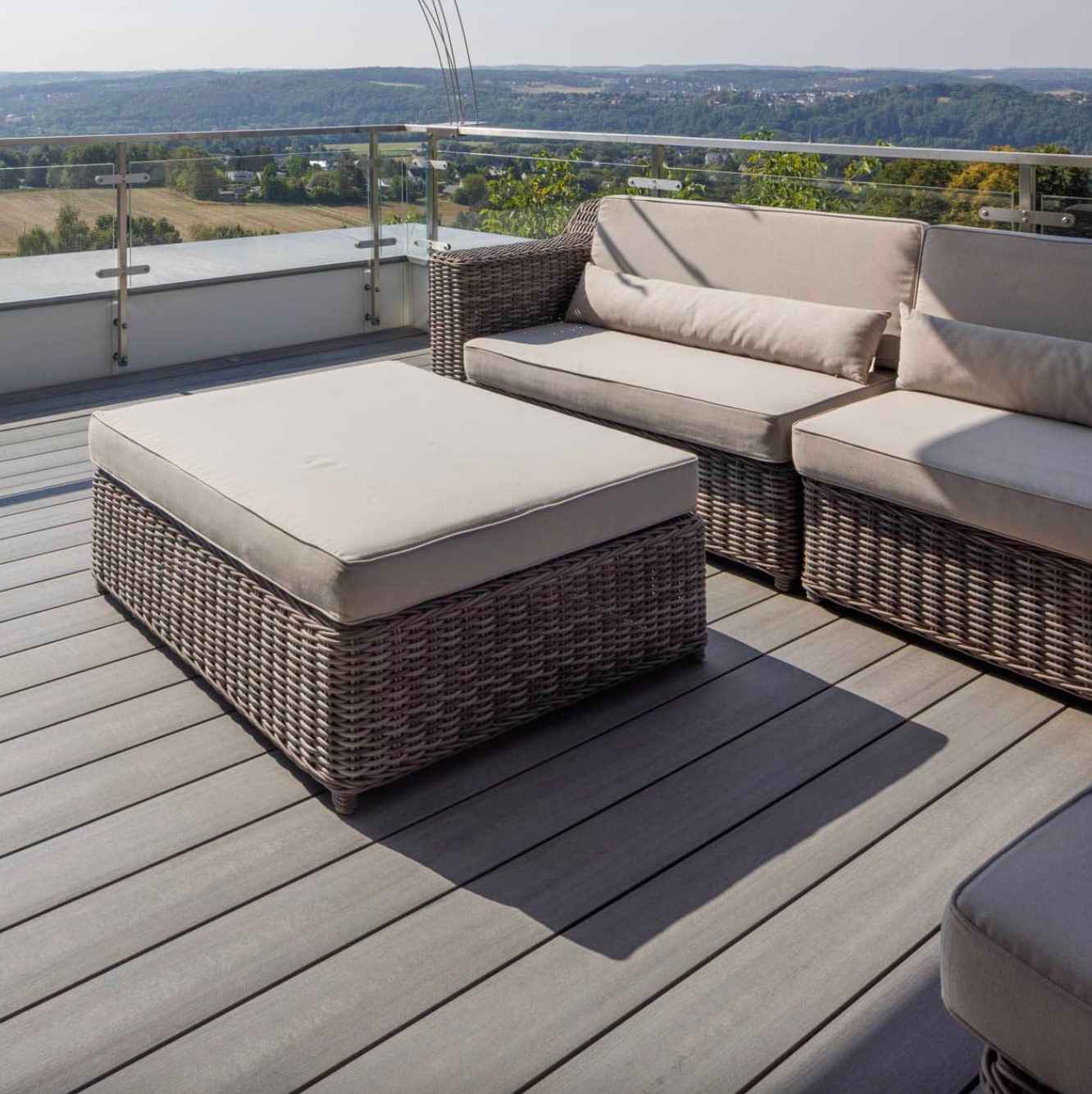 svetlosiva-wpc-terasa-s-ratanovym-sedenim-a-sklenenym-zabradlim-s-vyhladom-na-kopce-a-luka-pod-nimi-tichy-vidiecky-pokoj