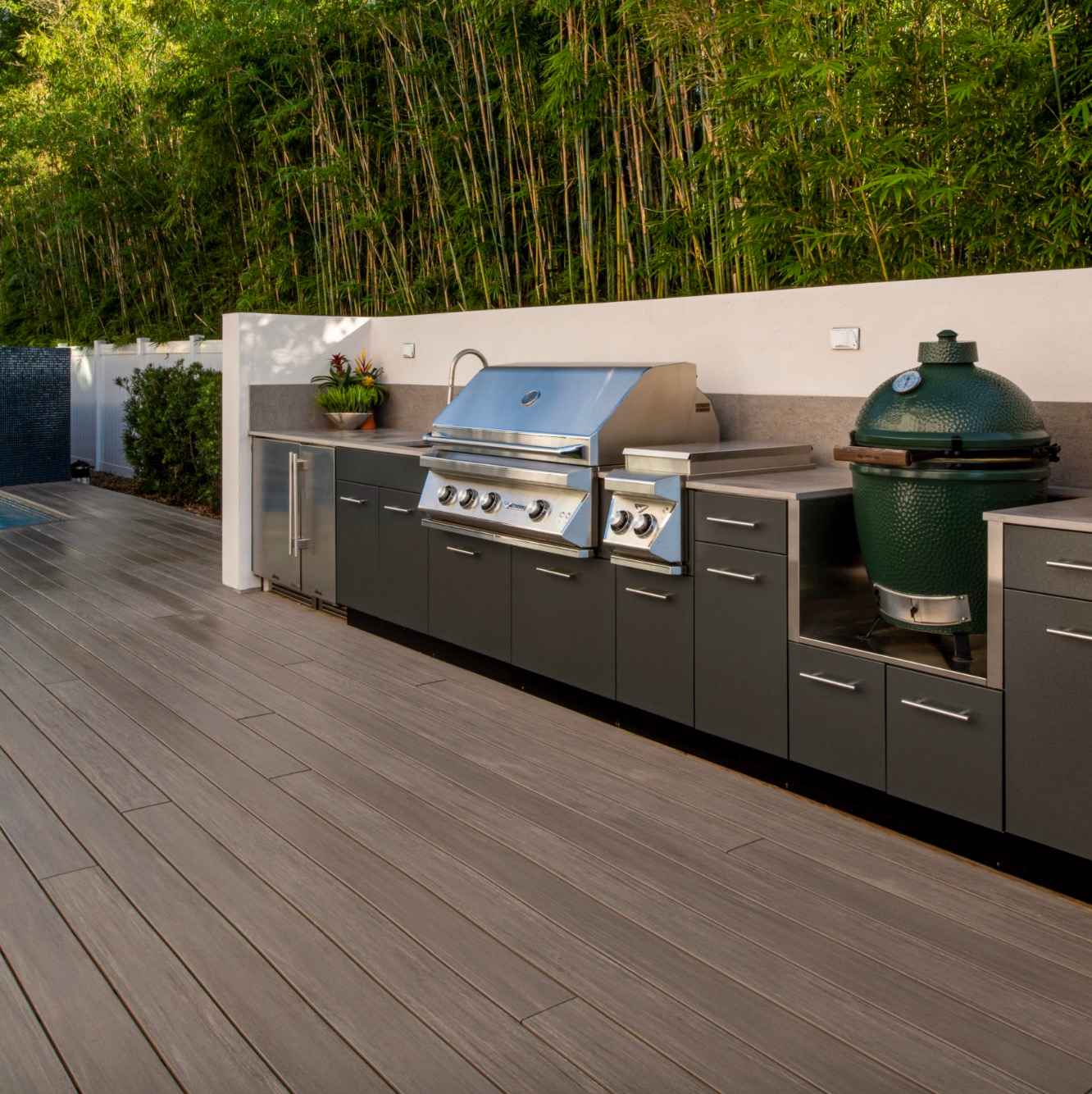 moderna-exterierova-kuchyna-na-wpc-terase-s-nerezovym-grilom-a-zelene-velke-keramicke-vajce-obklopena-bambusovym-plotom-letna-zahradna-party-atmosfera