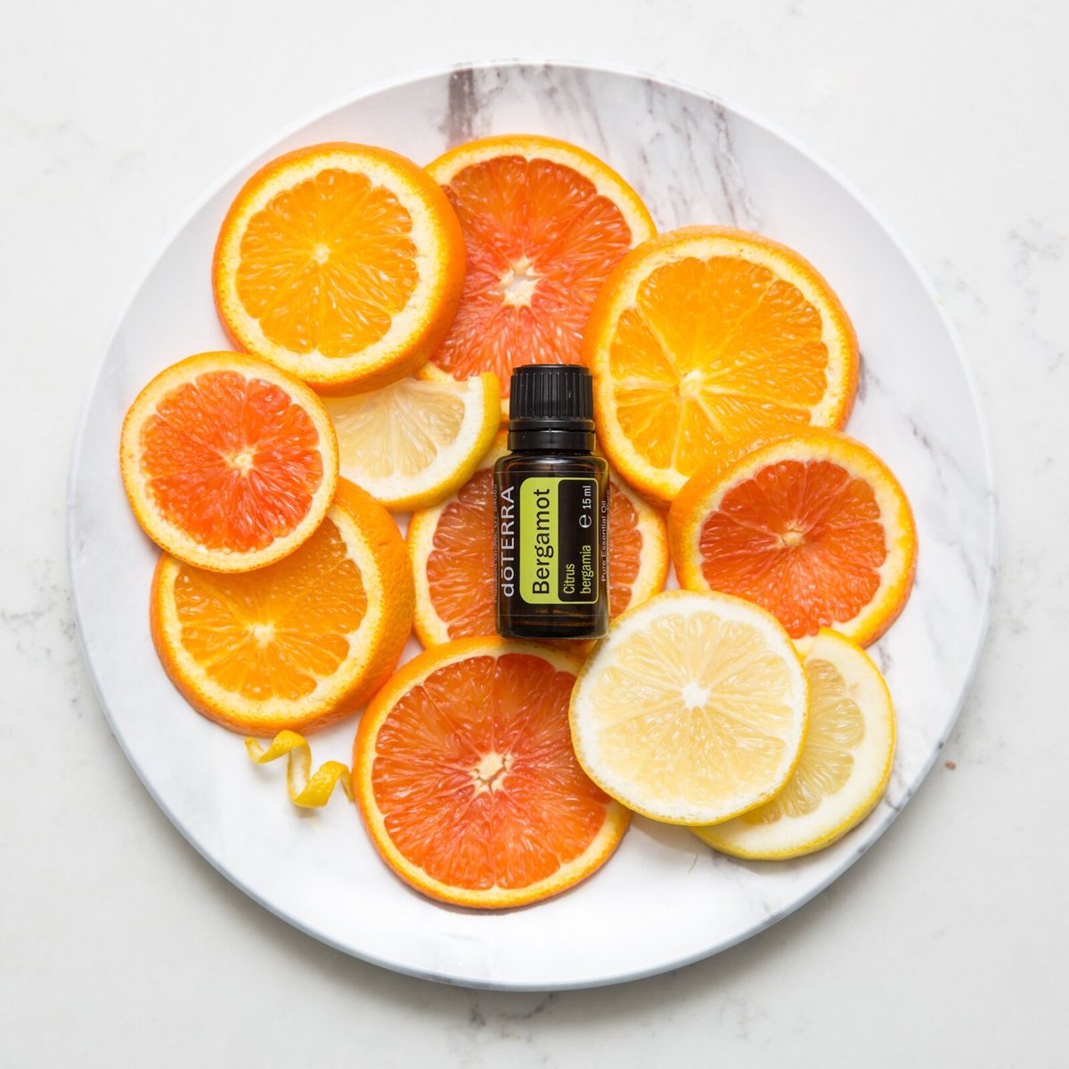 Fľaštička doTERRA Bergamot 15 ml na tanieri s plátkami pomaranča a citróna