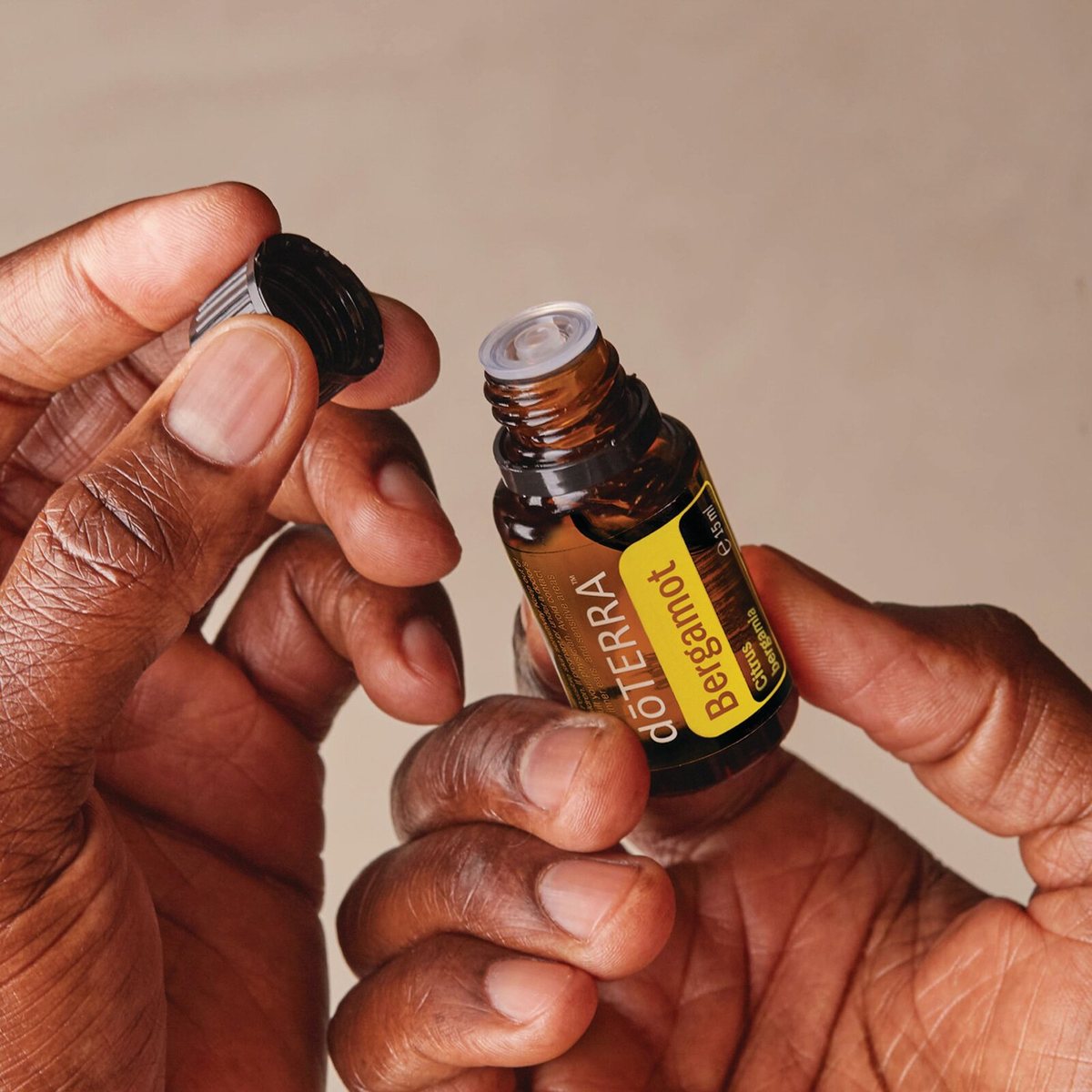 Ruky otvárajú fľaštičku doTERRA Bergamot