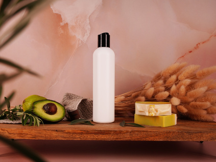 Bílá matná lahvička s disc top uzávěrem mezi přírodní kosmetikou na dřevěné poličce