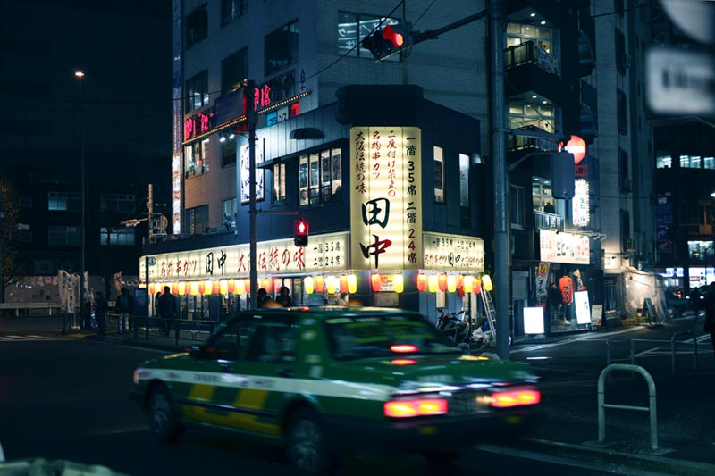 Noční tokijské nároží s jedoucím japonským taxíkem. V pozadí kušikatsu bistrem. Foto Petr Horčička