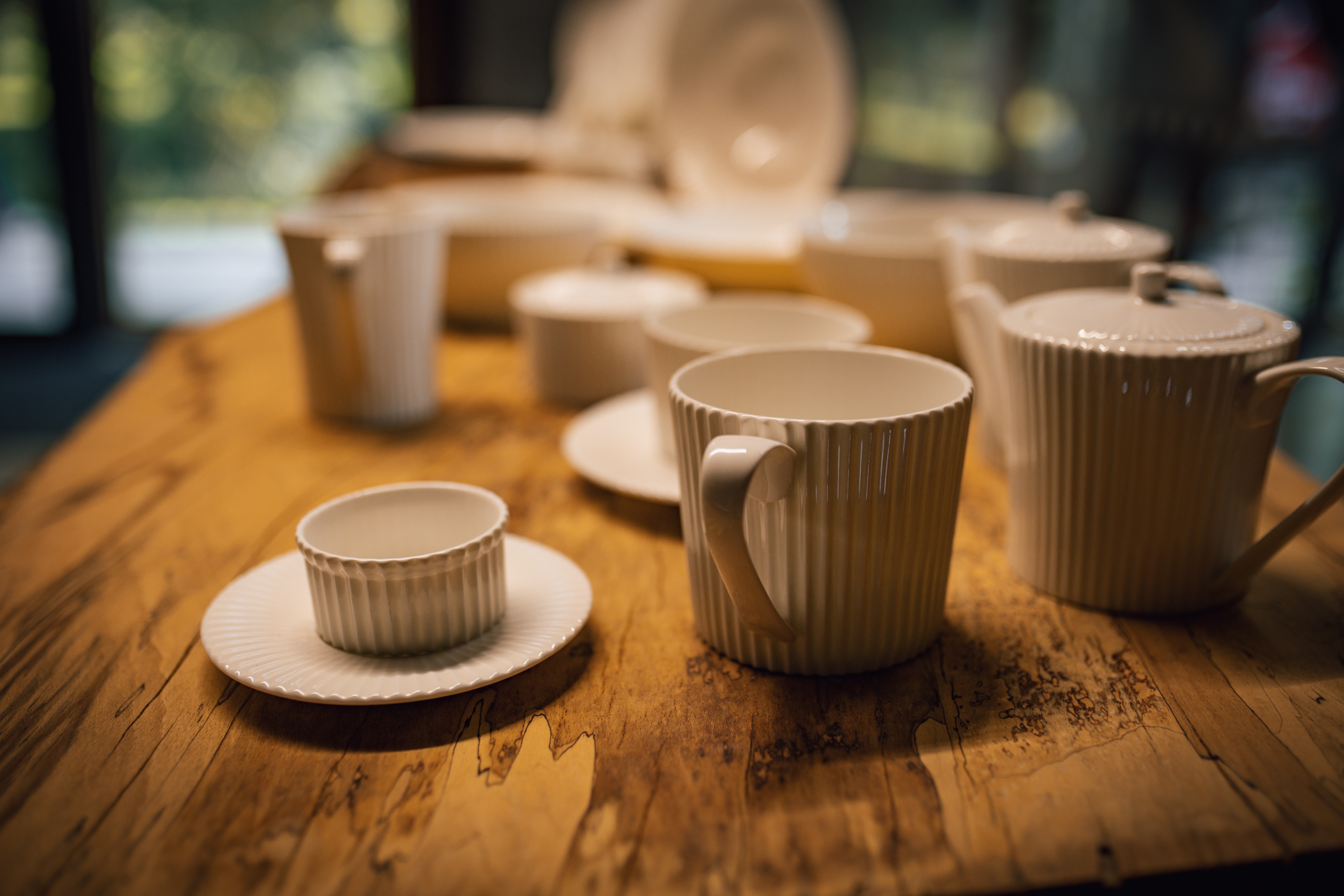 Expozice TOMGAST – dřevěný stůl s porcelánem, příbory a sklem pod logem TOMGAST