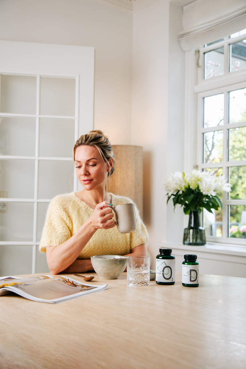 Žena pri raňajkách s Puori O3 omega-3 a Puori D3 na stole