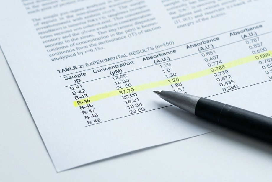 Detail vedeckej štúdie s tabuľkou dát a zvýrazneným riadkom, pero na papieri