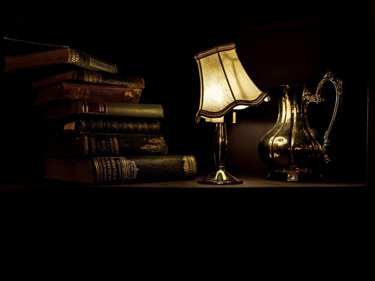 Stará lampa a stoh kníh v tlmenom svetle
