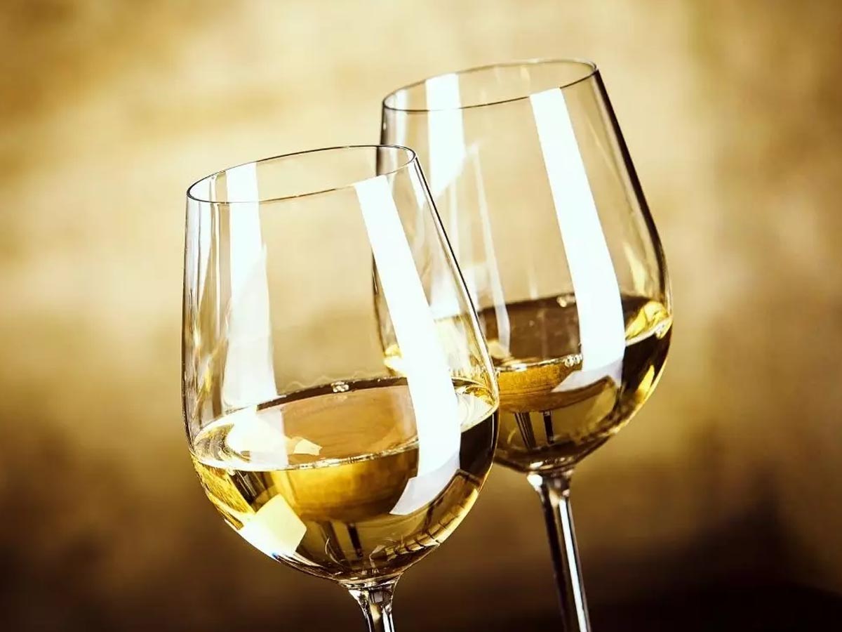 Pohár slamovo žltého vína z odrody pecorino proti svetlu