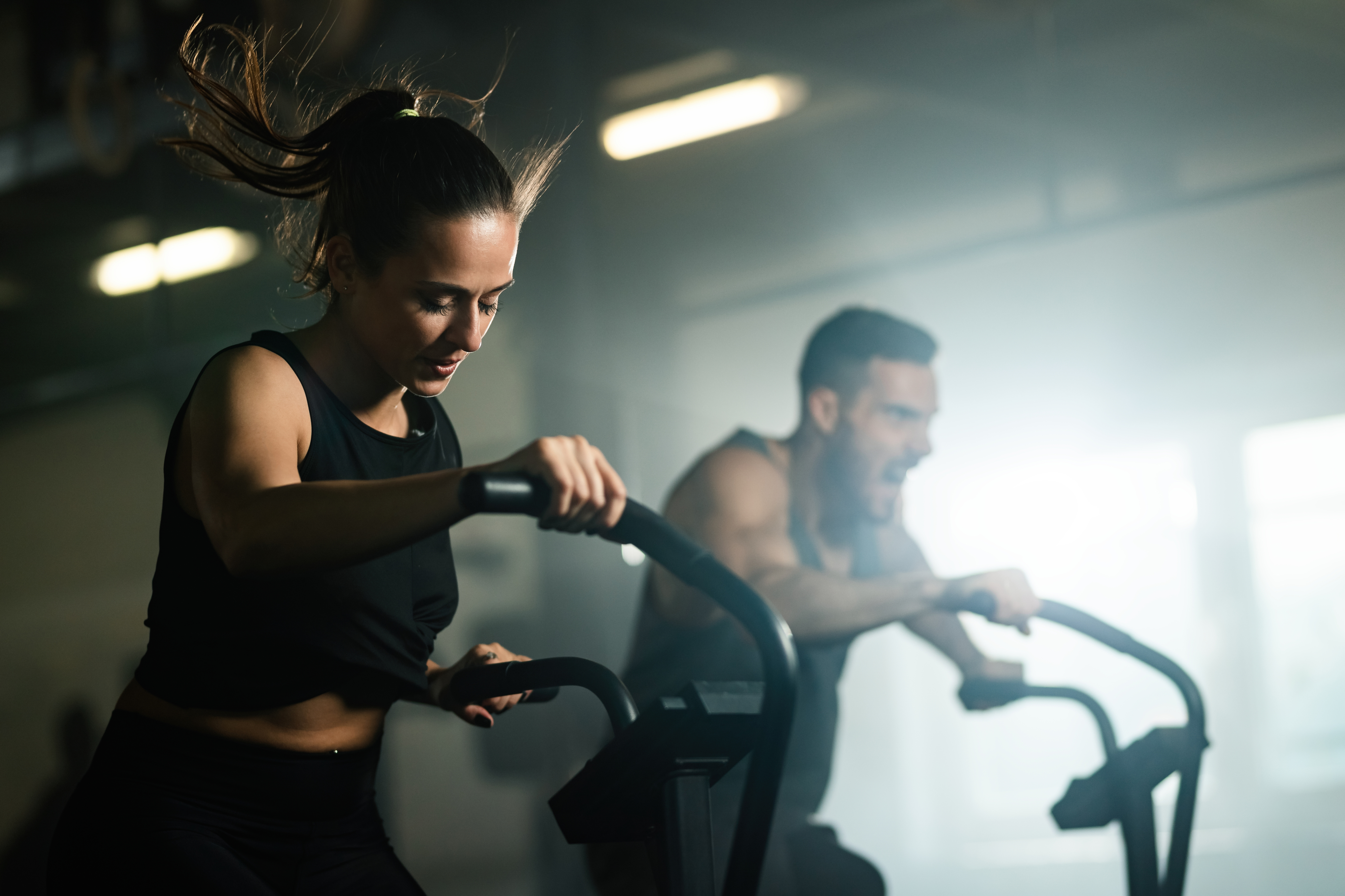 young-athletic-woman-having-cross-training-stationary-bike-gym