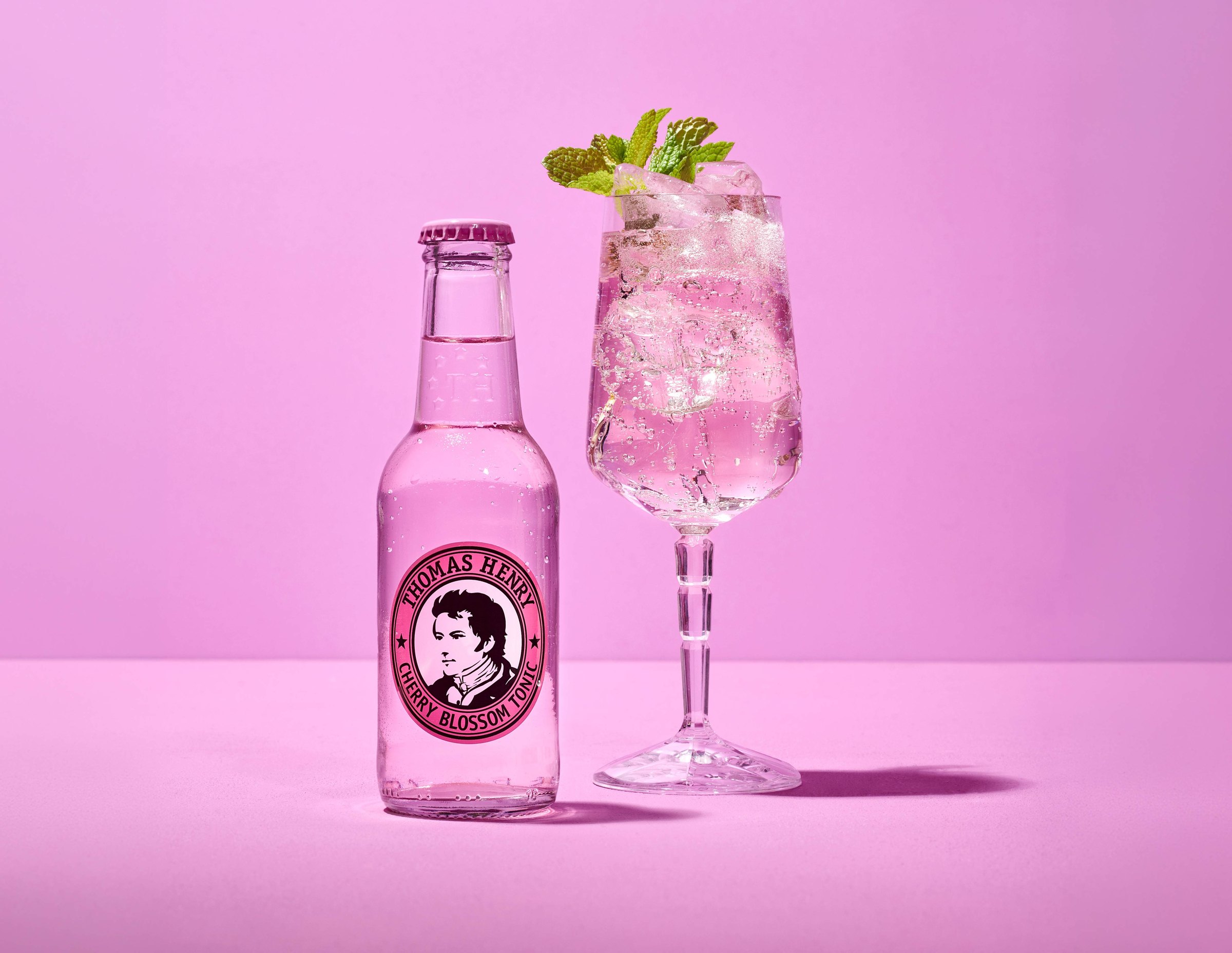 Láhev Thomas Henry Cherry Blossom Tonic a drink s mátou ve sklenici na víno