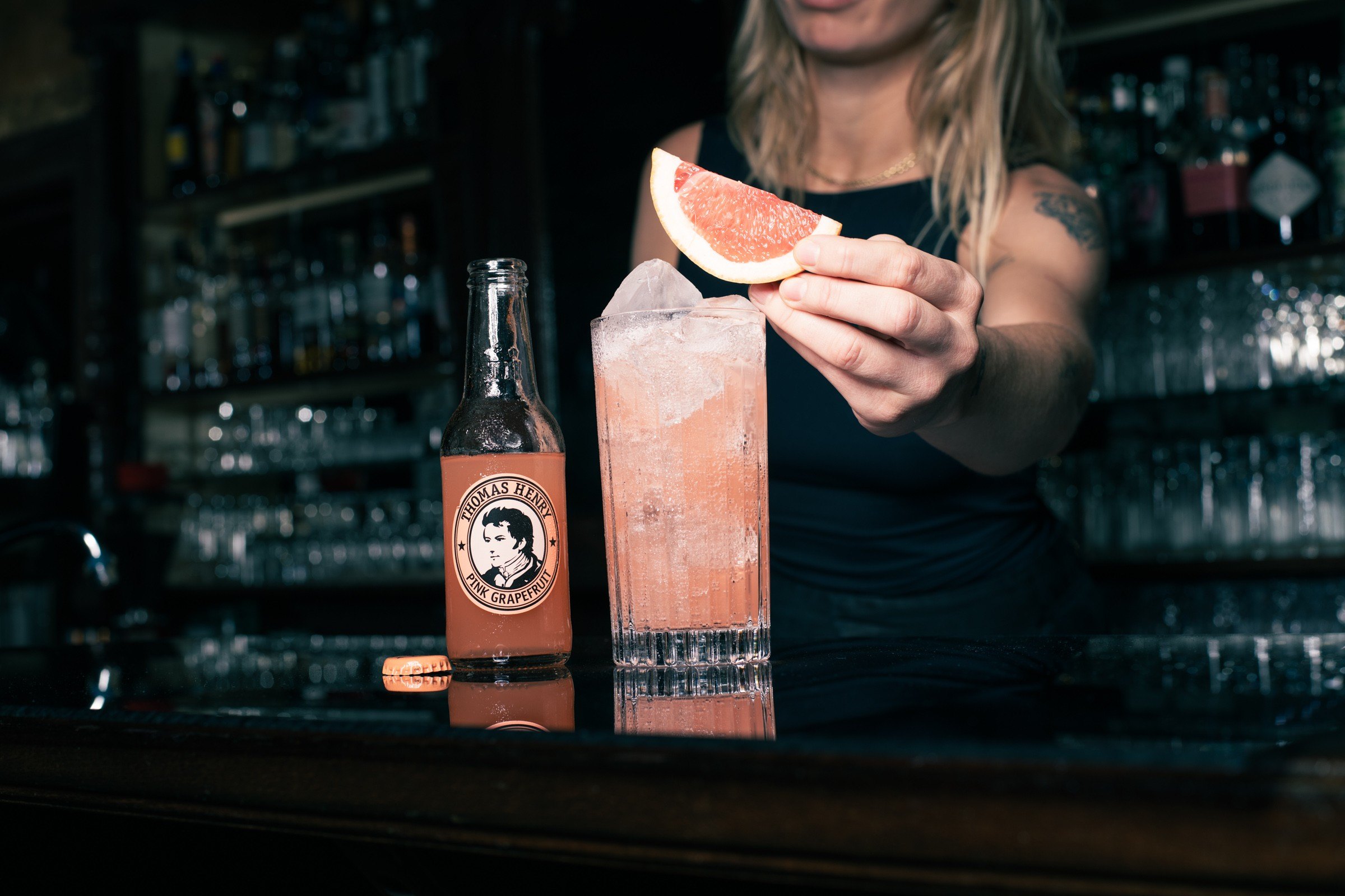 Barmanka zdobí drink plátkem grapefruitu