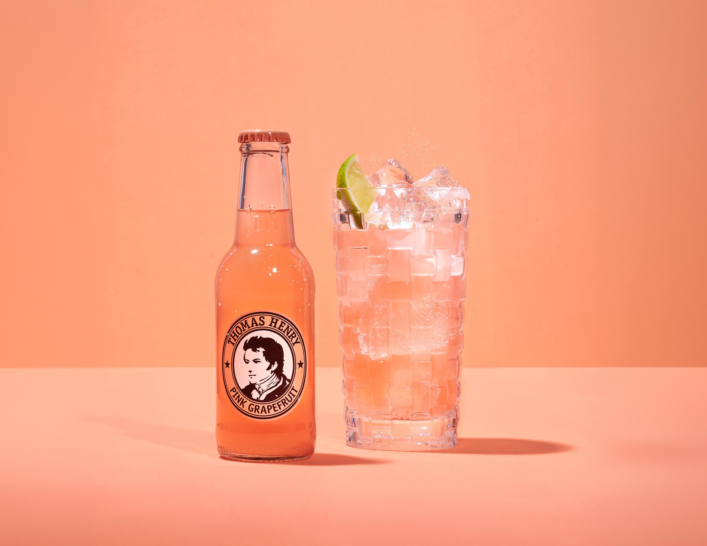 Láhev Thomas Henry Pink Grapefruit a sklenice s ledem a limetkou