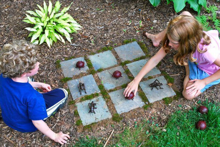 Dve deti hrajú spoločenskú hru na záhrade.