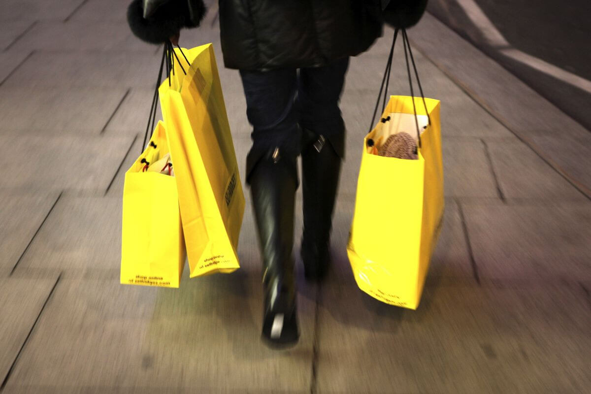Žena, ktorá nosí v rukách žlté nákupné tašky.