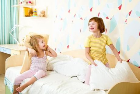Dve dievčatká na posteli v detskej izbe. 
