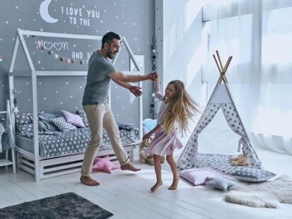 Otec tancujúci s dcérkou v detskej izbe. 