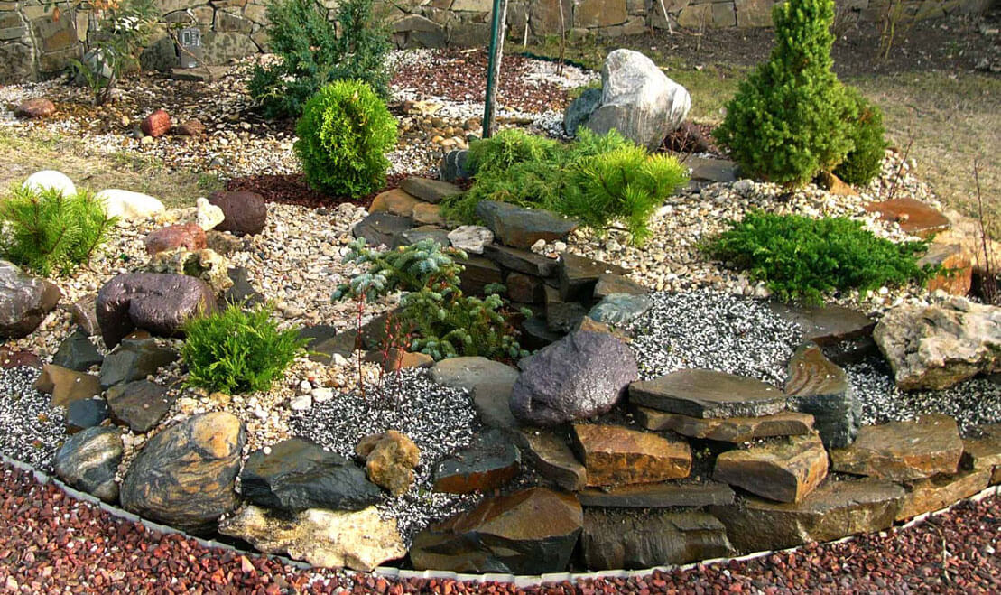 Záhradná skalka doplnená s kríkmi, štrkom a veľkými kameňmi 
