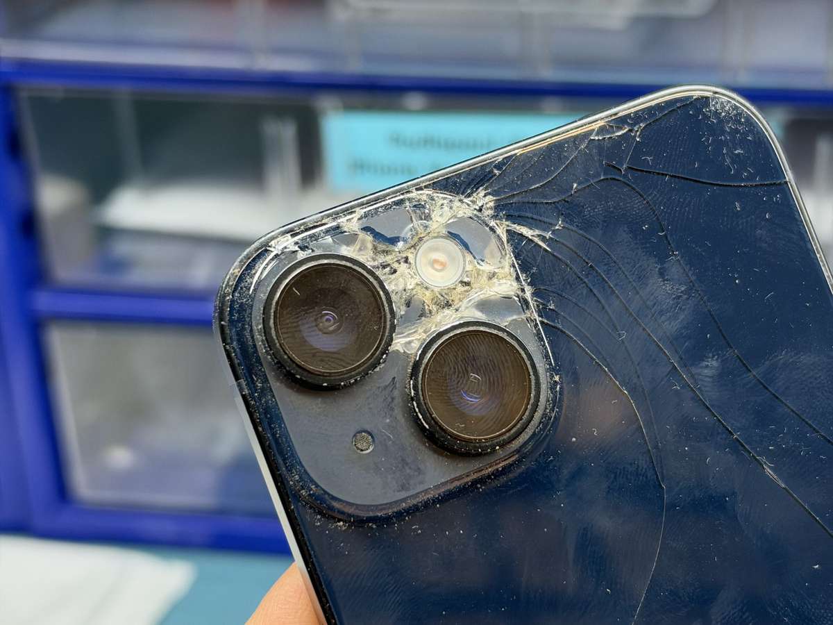 Detail sítě prasklin a drobných střepů zadního skla kolem kamer iPhonu 14