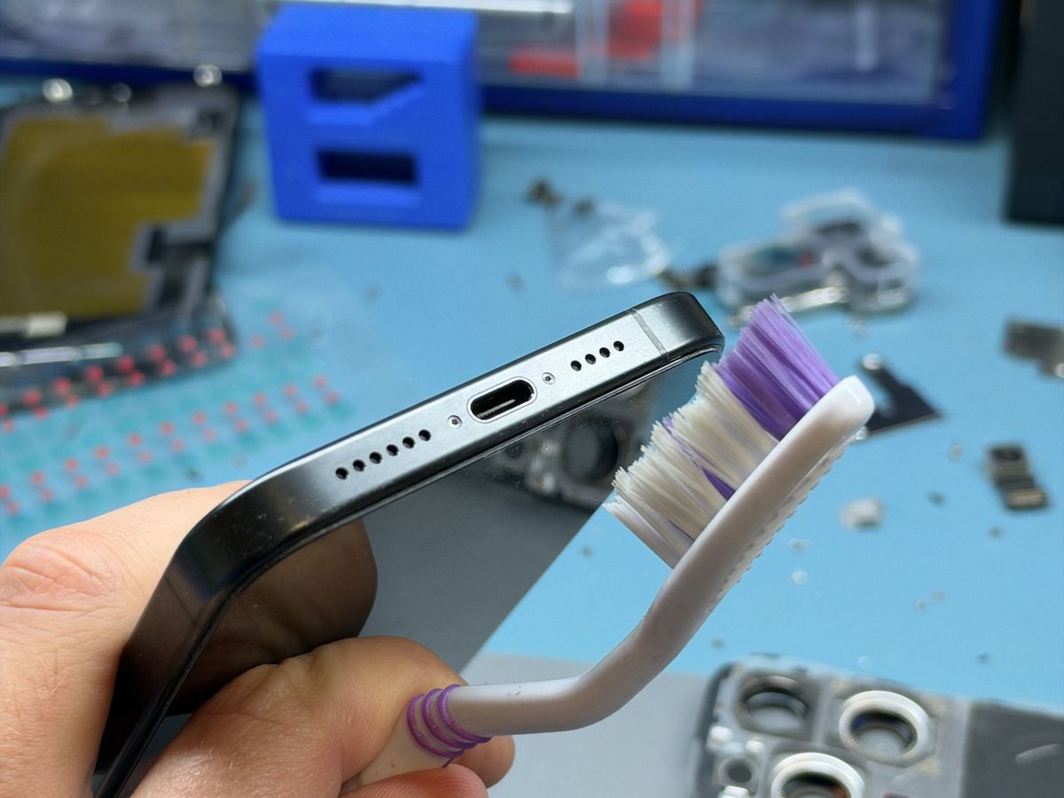 Kartáček s fialovými štětinami u vyčištěných mřížek iPhonu
