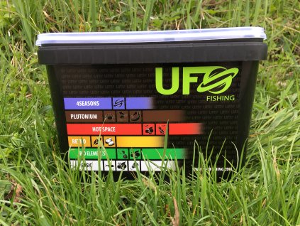 černý kbelík s boční samolepkou UFO Fishing v trávě