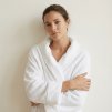 woman wearing white frote terry bathrobe shawl style, wjth the background of creamy white wall @White terry bathrobe