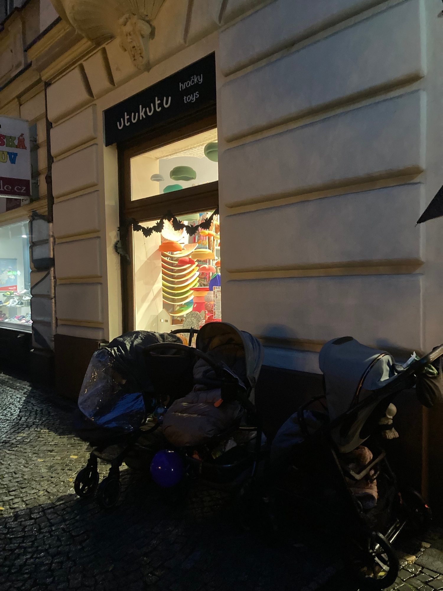 Večerní obchod Utukutu na Korunní ulici s kočárky koledníků před vchodem